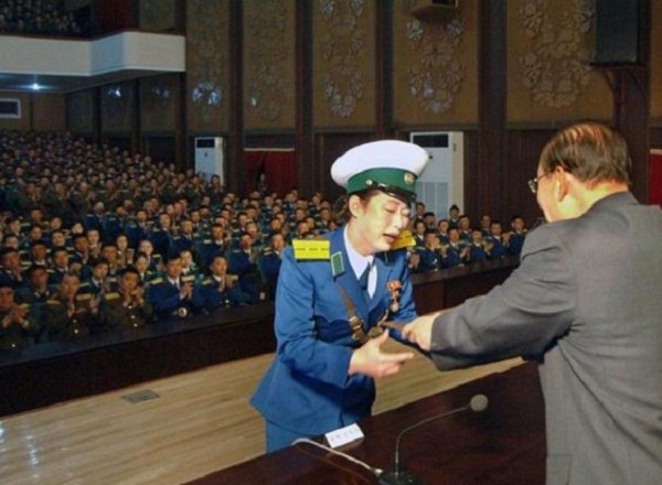 	Nữ cảnh sát giao thông Ri Kyong Sim được tặng huân chương anh hùng vì dập tắt một đám cháy gần nơi tấm áp phích hình ông Kim Jong Un.