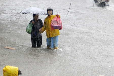 Một nhân viên Thoát nước Hà Nội giúp đỡ người dân vượt qua chỗ ngập sâu.