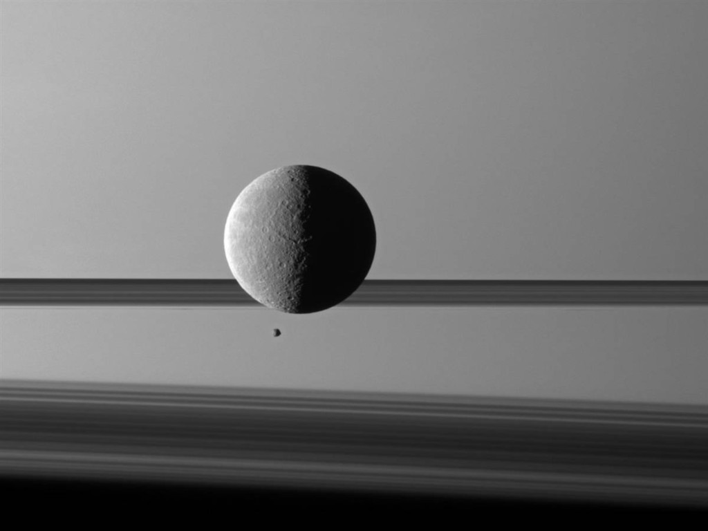 Hai mặt trăng Rhea và Epimetheus của sao Thổ sánh vai bên nhau.             Mặt trăng lớn Rhea và mặt trăng nhỏ Epimetheus cách nhau 150.000 dặm             (240.000 km). Các vệt đen phía sau là vành đai của sao Thổ.