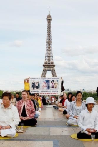 Các đệ tử Pháp Luân Công tập thiền định dưới bóng mát của tháp Eiffel, Paris rất thanh bình đối lập với sự đàn áp đang sảy ra ở Trung Quốc.