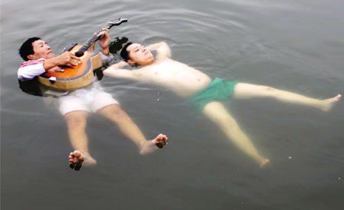 1 Ông Hứa Văn Bạch (trái) đàn guitar còn ông Hứa Tây Hạ hát vọng cổ trong tư thế thả nổi trên mặt nước gần 4 giờ. Ảnh: Vietkings