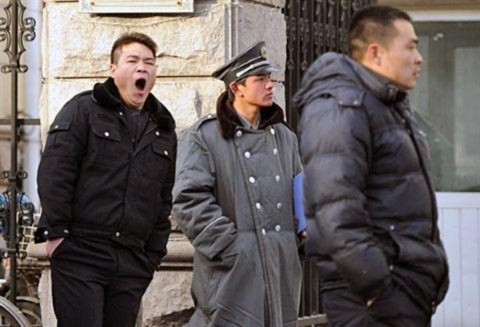 Công an mặc thường phục (trái và phải) canh phía ngoài nhà của nhân vật bất đồng chính kiến đang bị cầm tù Lưu Hiểu Ba