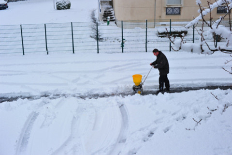 Các lối đi bộ được xúc tuyết và rải muối chống trơn trượt. Người đàn ông này đang đẩy một cái xe rải muối.
