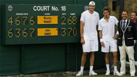 Hai tay vợt Isner và Mahut đứng cạnh bảng tỷ số của trận đấu.