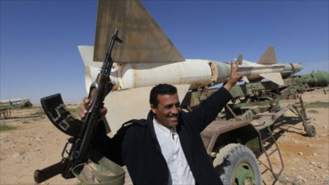 Một người biểu tình chống Gaddafi ăn mừng bên căn cứ quân sự bị bỏ không tại phía đông Libya. Ảnh: AP