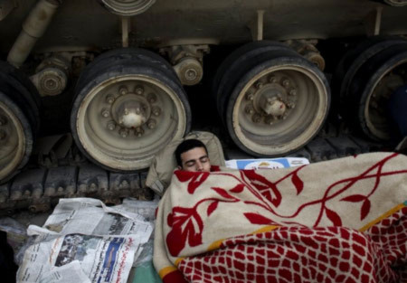 Người biểu tình ngủ dưới chân bánh xích xe tăng tại quảng trường Tahrir Cairo. Ảnh: AP