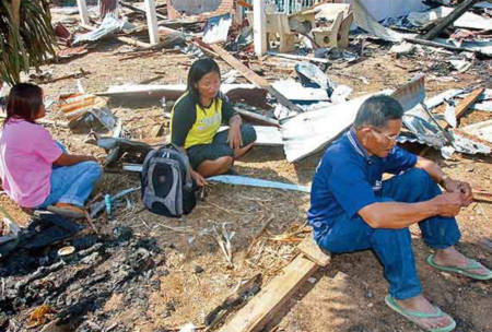 Một gia đình người Thái ngồi bên ngôi nhà bị hư hại hoàn toàn sau giao tranh giữa binh sĩ Thái Lan và Campuchia. Ảnh:
