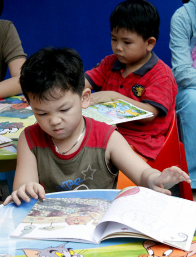 Một cậu bé chăm chú xem một cuốn truyện tranh tại gian dành riêng cho độc giả nhỏ tuổi.