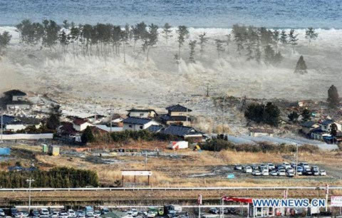 Sóng thần nhấn chìm nhà cửa ven biển ở vùng đông bắc Nhật. Ảnh: Xinhua.