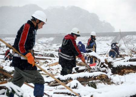 Các nhân viên cứu hỏa tìm kiếm nạn nhân động đất và sóng thần khi tuyết rơi tại thành phố Miyagi, tỉnh Iwate hôm 16/3. Ảnh: AFP.