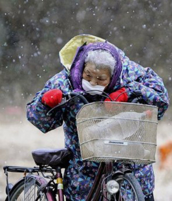 Bà cụ chở nước bằng xe đạp khi tuyết rơi hôm 16/3. Ảnh: AP.