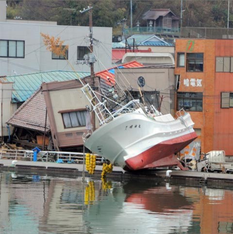 Tàu đánh cá nằm giữa phố sau khi bị sóng thần cuốn đi tại tỉnh Miyagi. Ảnh: AFP.