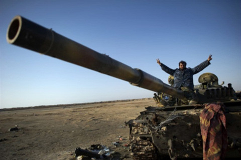 Một binh sĩ thuộc phe đối lập ở Libya ngồi trên chiếc xe tăng bị phá hoại tại lối vào thành phố Ajdabiya. Ảnh: AFP.