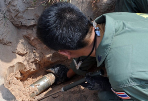 Một binh sĩ Thái Lan xử lý quả đạn pháo chưa nổ, sau một vụ giao tranh xuyên biên giới với Campuchia. Ảnh: AFP