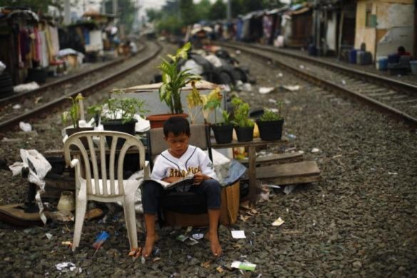 Một cậu bé ngồi đọc sách thản nhiên giữa hai đường ray ở thủ đô Jakata, Indonesia.