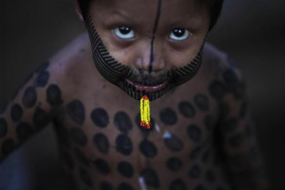 Một bé trai thuộc tộc người Kayapo, Brazil xăm người theo tục lệ truyền thống.
