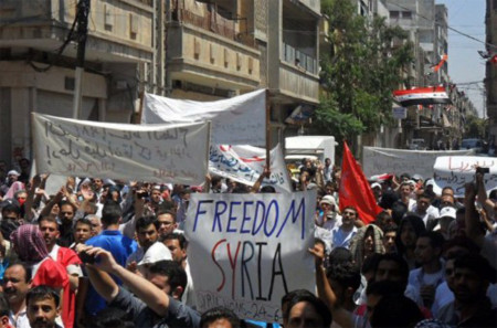 Người biểu tình giương cao các biểu ngữ tại thành phố Homs, cách thủ đô Damacus khoảng 160 km. Ảnh: AFP