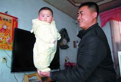 Bé gái 4 tháng tuổi đứng trên bàn tay bố.