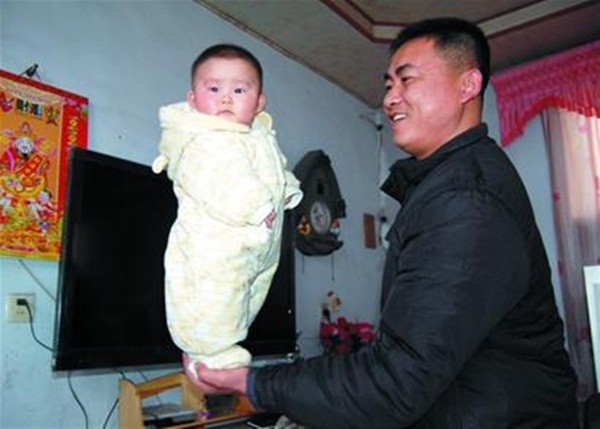 Bé gái 4 tháng tuổi đứng trên bàn tay bố.