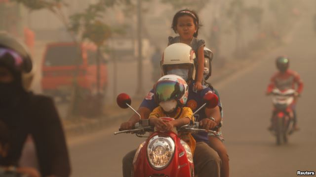 Một gia đình đi xe máy qua lớp khói mù trong thị trấn Duri ở tỉnh Riau của Indonesia, ngày 24/6/2013.