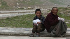 Người đàn ông và một cậu bé Tây Tạng ngồi gần Tu viện Jonang Dzamthang. Trung Quốc nhấn mạnh rằng các vụ dời cư là hoàn toàn trên căn bản tự nguyện và người dân Tây Tạng biết ơn vì có được nhà mới.
