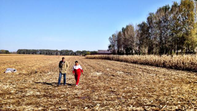 Former Masanjia inmate Liu Hua (right) walks across the field outside the female inmates' quarters and talks to a CNN reporter.