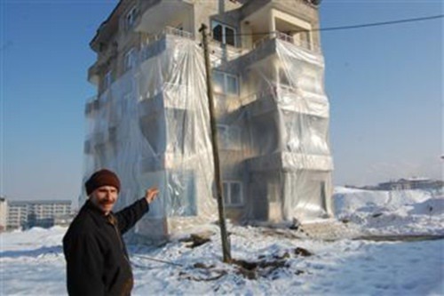 Ông Huseyin Arme đứng trước tòa nhà đã được bọc nylon ba tầng. Ảnh: DHA