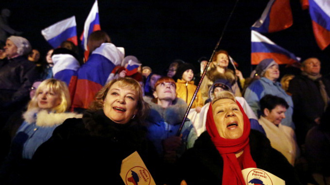 Hai phụ nữ cầm cờ Nga chờ nghe kết quả sơ bộ cuộc trưng cầu dân ý - Ảnh: Reuters