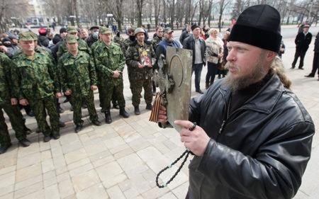 Một linh mục Chính thống giáo giữ một biểu tượng tôn giáo đứng với người ủng hộ Nga trong một cuộc biểu tình trước tòa nhà chính quyền khu vực trong trung tâm công nghiệp chán nản của Lugansk