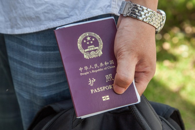 Một công dân Trung Quốc cầm Hộ chiếu Trung Quốc ngày 16/5/2014. Chính quyền đang thắt chặt yêu cầu giấy tờ đi lại của các quan chức Trung Quốc, nhằm ngăn chặn họ trốn chạy khỏi Trung Quốc. (Omar Havana/Getty Images)