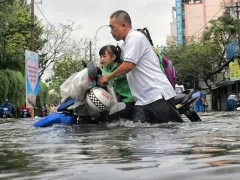 Nước ngập gần đến yên xe khiến phụ huynh vất vả đón con.
Photo: Minh Quan/tinmoitruong