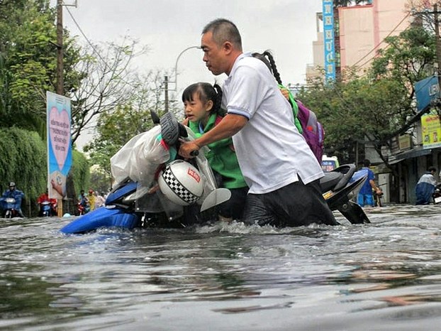 Nước ngập gần đến yên xe khiến phụ huynh vất vả đón con.
 Photo: Minh Quan/tinmoitruong