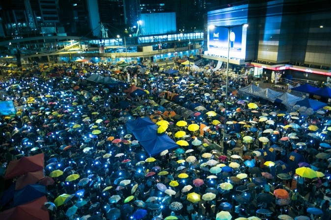 Hàng ngàn người đã giương ô và vẫy điện thoại tại Admiralty, Hồng Kông, ngày 28/10/2014, yêu cầu một chế độ dân chủ hơn. Hiện chưa thể thấy được kết cục nào rõ ràng cho chiến dịch đã kéo dài hơn một tháng nay. (Ảnh Benjamin Chasteen/ Báo Đại Kỷ Nguyên)