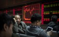 Những người giao dịch chứng khoán Trung Quốc trò chuyện trước bảng hiển thị các mã chứng khoán tại một công ty môi giới chứng khoán ở Bắc Kinh, Trung Quốc, ngày 22/1/2015. (Kevin Frayer / Getty Images)