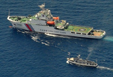 Một chiếc chiến thuyền Bảo vệ Bờ biển của Trung Quốc (phía trên) và một chiếc thuyền cung ứng của Philippines rơi vào tình trạng giằng co vì tàu Philippines muốn tiến đến Bãi Cỏ Mây (Second Thomas Shoal), một rạn san hô xa xôi ở Biển Đông được cả hai nước tuyên bố chủ quyền, ngày 29 tháng 3 năm 2014 ( Jay Directo/AFP/Getty Images)