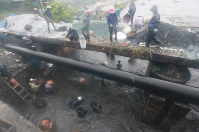 Hàng chục người dân vớt than trong cơn mưa trắng trời dưới dòng nước lũ cuồn cuộn chảy - Ảnh: Tiến Thắng