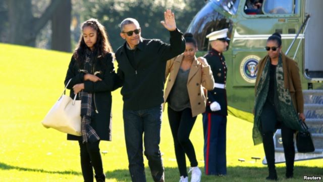 Tổng thống Mỹ Barack Obama vẫy chào khi ông đi cùng Đệ nhất Phu nhân Michelle Obama (phải) và hai người con gái của họ là Malia (trái) và Sasha trên Bãi Cỏ Nam Tòa Bạch Ốc, Washington, ngày 3 tháng 1, 2016. 