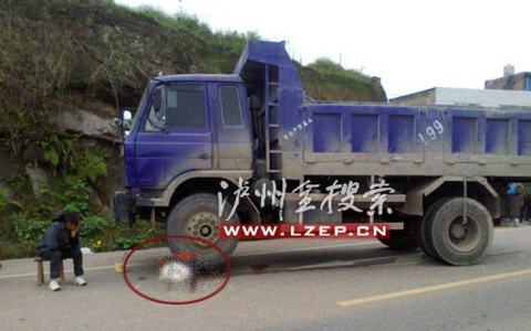 Mẹ của Xiong Maoke ngồi thất thần cạnh thi thể em đang mắc kẹt dưới bánh xe tải (trong vòng tròn đỏ). Ảnh: Lzep.cn